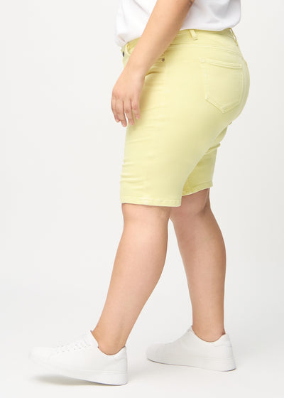 Lysegule skinny middle shorts set fra siden på en plus-size model.