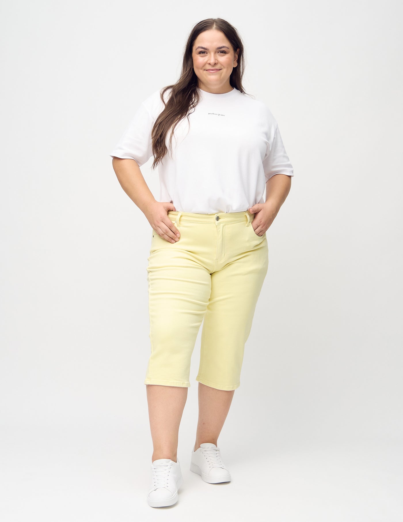 Fuldt billede af en plus-size model i lysegule regular capris.