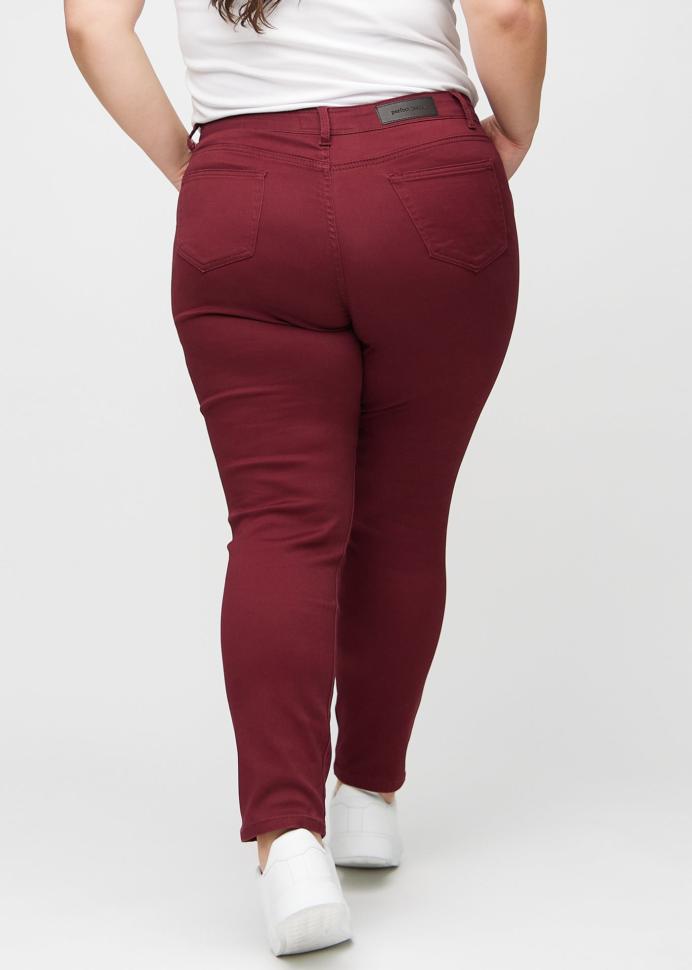 Mørkerøde slim jeans set bagfra på en plus-size model, så man kan se hele produktet.