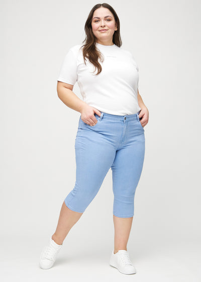 Plus-size model går ind i billedet, strækker i sine capris, viser dem frem ved at dreje rundt, og forlader derefter billedet.